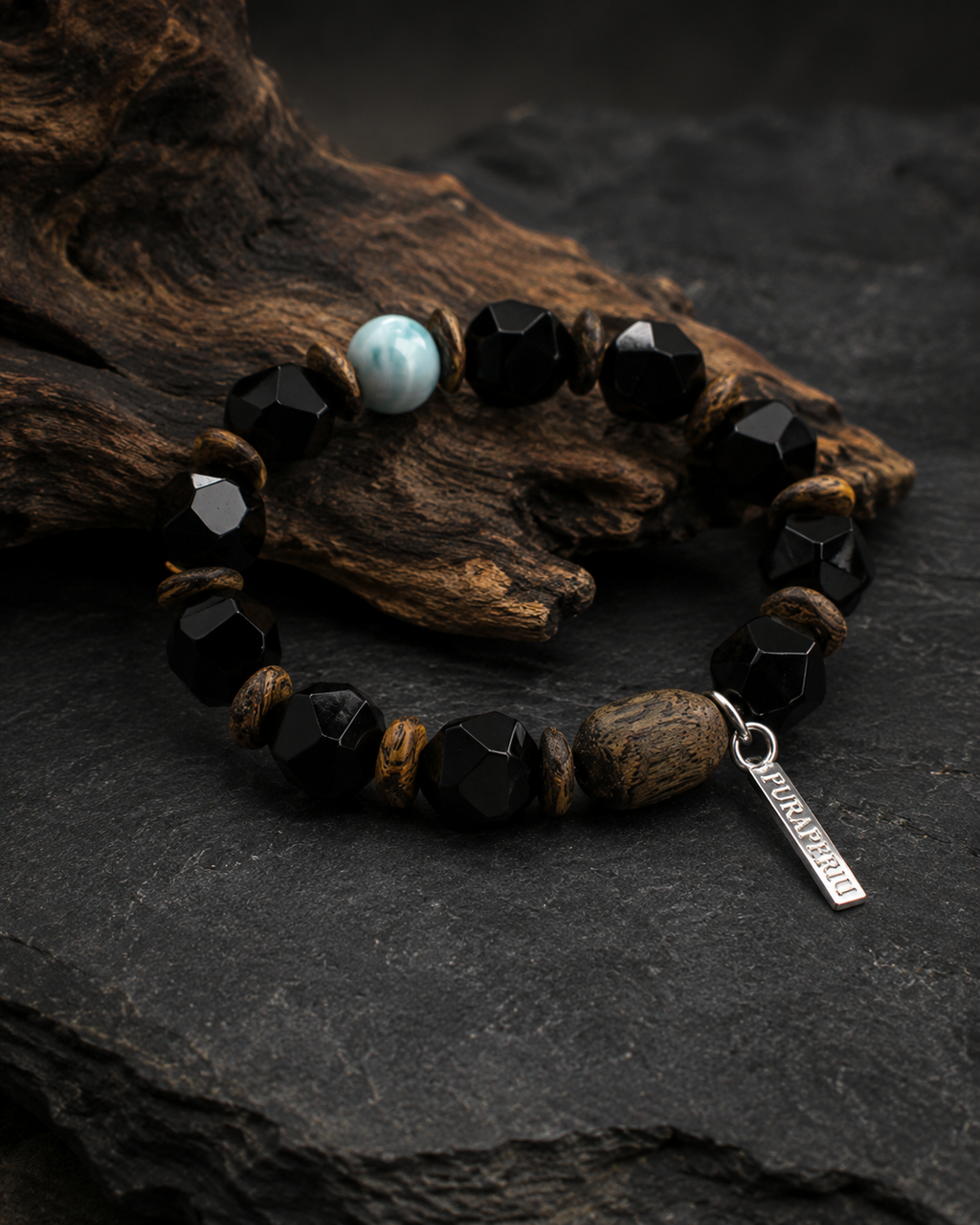 Unisex black agate bracelet displayed on dark stone and natural wood